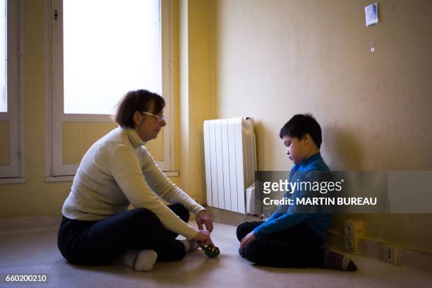 An assistant takes care of Jules, a 8-year-old autistic boy, on March 24, 2017 in Courbevoie, north-west of Paris, at the Lud'Eveil center for...