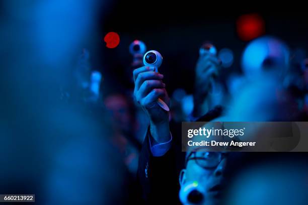 Members of the audience take photos as they hold up a new version of the Samsung Gear 360 camera, which was distributed to the crowd, during a launch...