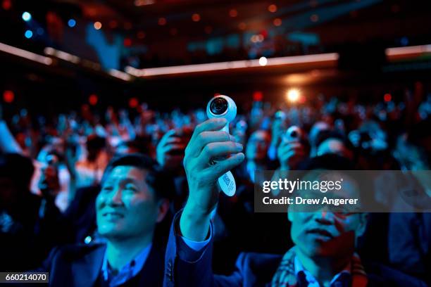 Members of the audience take photos as they hold up a new version of the Samsung Gear 360 camera, which was distributed to the crowd, during a launch...