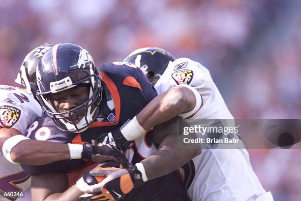 Duane Starks and Corey Harris of the Baltimore Ravens tackle Dwayne Carswell of the Denver Broncos during the third quarter of the game at Mile High...