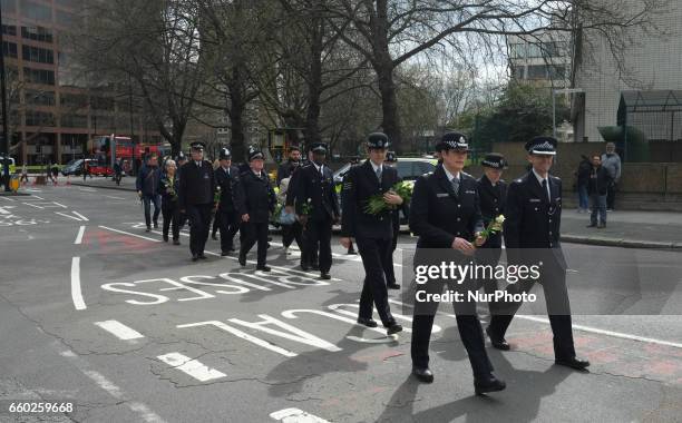 Police officers hold flowers on Westminster Bridge during a vigil to remember the victims of last week's Westminster terrorist attack on March 29,...