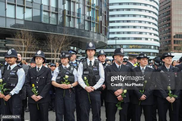 Police officers hold flowers on Westminster Bridge during a vigil to remember the victims of last week's Westminster terrorist attack on March 29,...