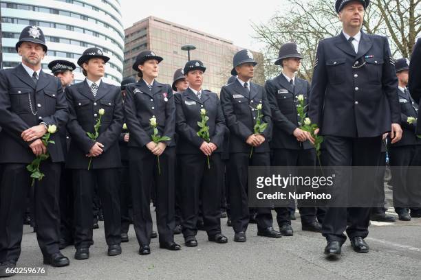 Police officers hold flowers on Westminster Bridge during a vigil to remember the victims of last week's Westminster terrorist attack on March 29,...