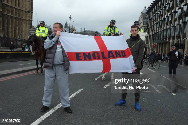 Two men hold a St George's Cross flag with 'England' written on it on Westminster Bridge as people attend a vigil to remember the victims of last...