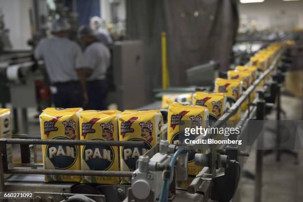 Sacks of Empresas Polar SA P.A.N. Brand cornmeal moves along a conveyor belt at the company's processing and distribution facility in Turmero,...