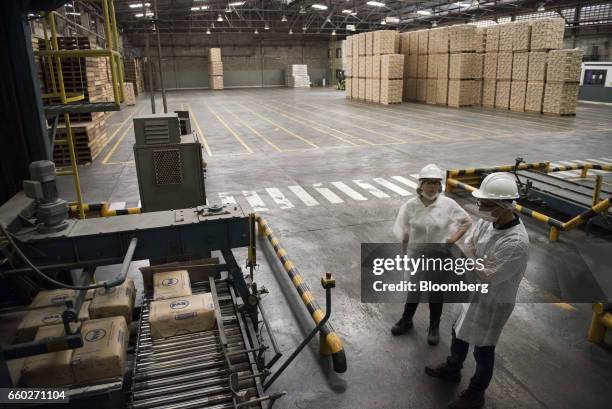 Employees watch as sacks of Empresas Polar SA P.A.N. Brand cornmeal are packaged for transport at the company's processing and distribution facility...