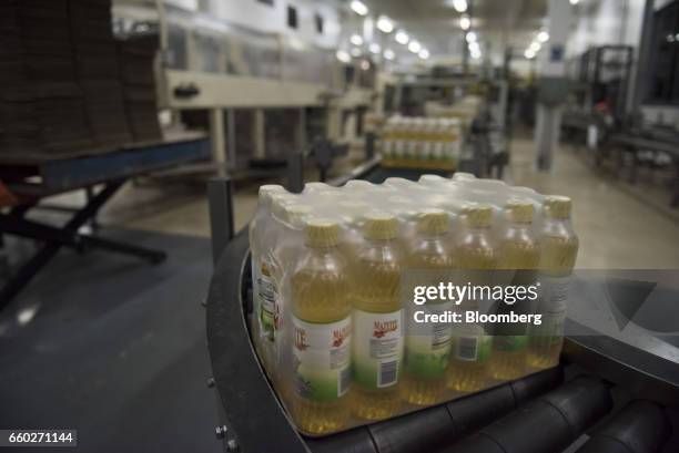 Packages of Empresas Polar SA Mazeite brand corn oil bottles move along a conveyor belt at the company's processing and distribution facility in...