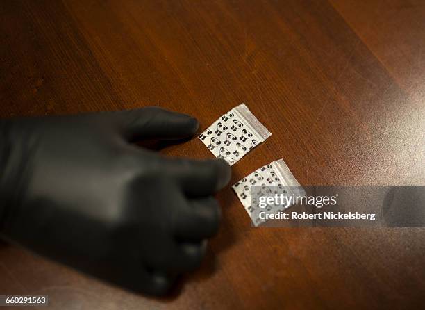 Member of the narcotics squad from the Burlington Police Department displays two bags of heroin taken from a suspect following a purchase from a drug...