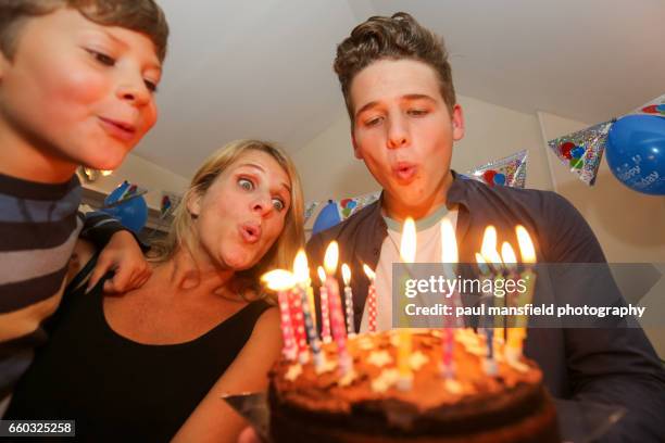 teenager and family blowing out candles on  birthday cake - 2015 18 stock pictures, royalty-free photos & images