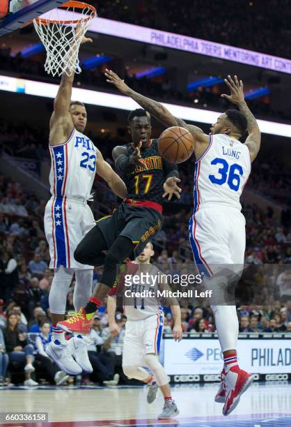 Dennis Schroder of the Atlanta Hawks passes the ball against Justin Anderson and Shawn Long of the Philadelphia 76ers in the first quarter at the...