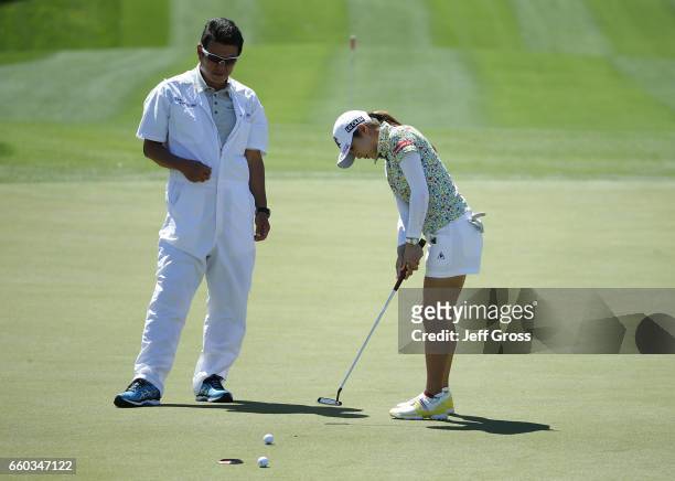 Bo-Mee Lee of the Republic of Korea putts on the fourth green, as her caddie Nori Shimizu looks on during a pro am at Mission Hills Country Club on...