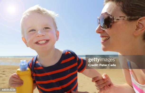 mother and son on beach with suntan lotion - sun safety stock pictures, royalty-free photos & images