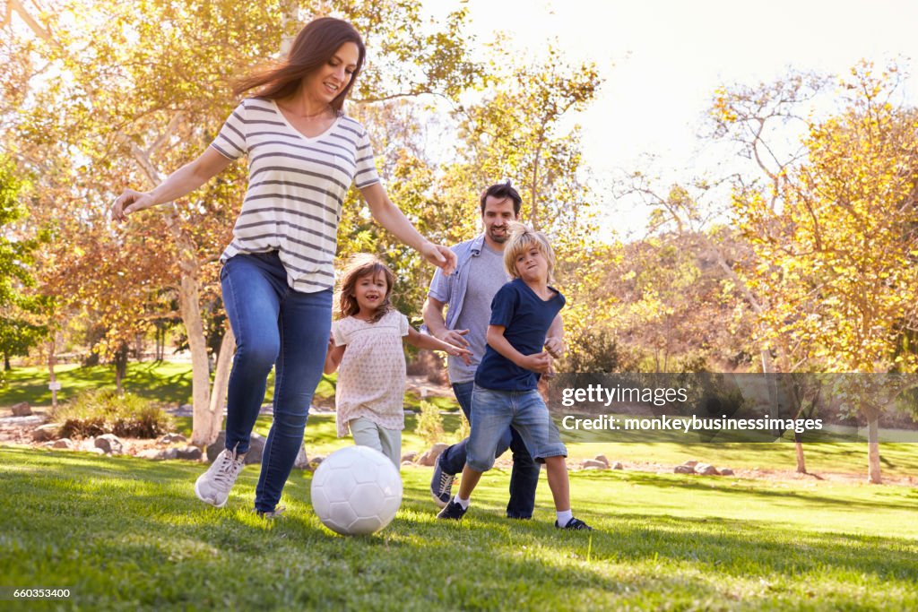 Familj spelar fotboll i parken tillsammans