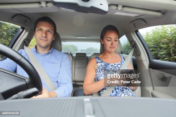 couple in car, woman looking at phone - man and woman and car stock pictures, royalty-free photos & images