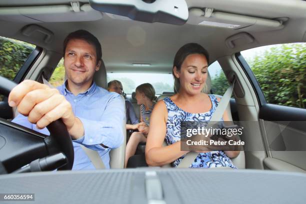 family in car, mum looking at phone - inside car stockfoto's en -beelden