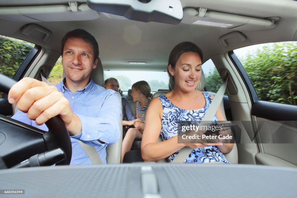 Family in car, mum looking at phone