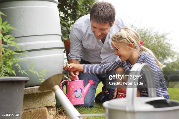 father and daughter getting water from water butt - vattenhushållning bildbanksfoton och bilder