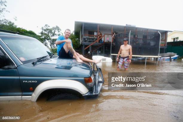 Bennett Wood sits on his car after flood waters entered his back yard on March 30, 2017 in Murwillumbah, Australia. Heavy rain and flash flooding is...