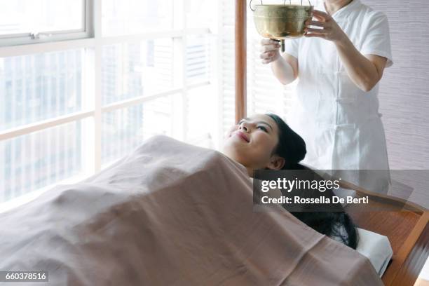 young woman having ayurveda spa massage - shirodhara stock pictures, royalty-free photos & images