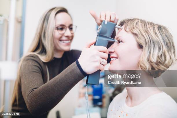 vrouwelijke optometrist voert oogonderzoek - eye exam stockfoto's en -beelden