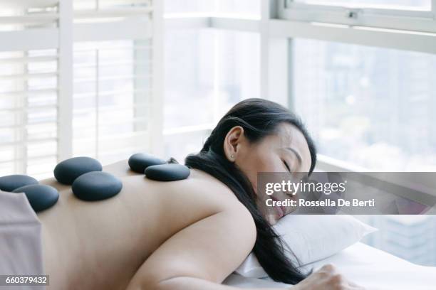 adult woman enjoying hot stone massage - de salon stock pictures, royalty-free photos & images