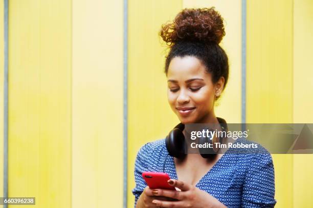 woman with headphones using smart phone - topknot stock pictures, royalty-free photos & images