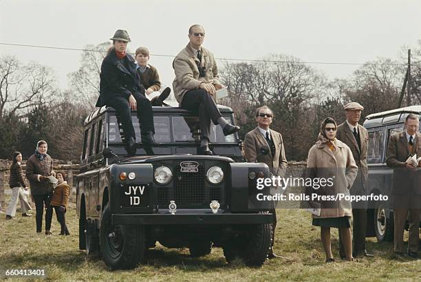 Members of the British royal family, including Queen Elizabeth II standing with Henry Somerset, 10th Duke of Beaufort beside a Land Rover Series IIA...