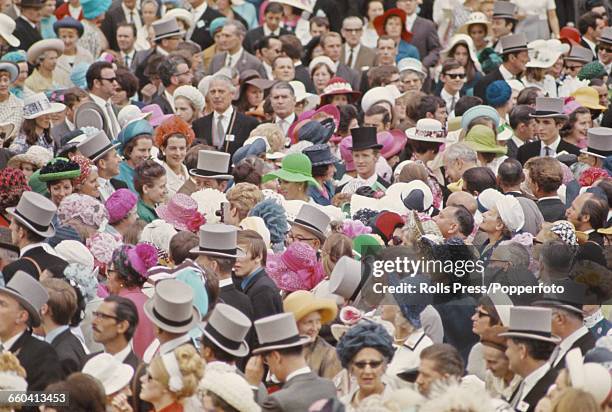 Wearing a bright green hat, Princess Anne makes her way through crowds of racegoers in formal attire to the Royal Enclosure at Royal Ascot race...