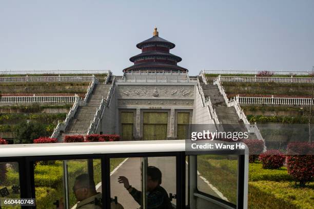 An electric vehicle carries passengers passed the commercial cemetery, which looks like the Temple of Heaven, on March 29, 2017 in Wuhan, Hubei...