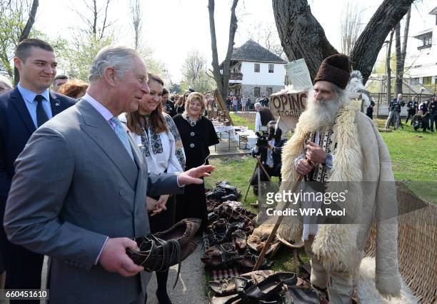 Prince Charles, Prince of Wales is given some shoes during a visit to the Village Museum on the second day of his nine day European tour on March 30,...