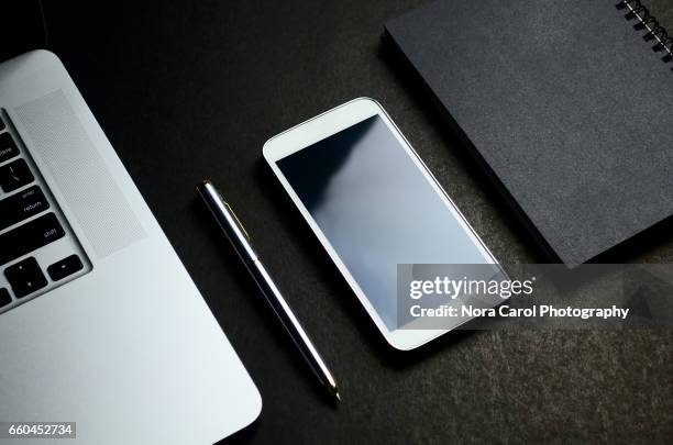 elegance top view shot of laptop, pen, smart phone and black note pad - blank book on desk stock pictures, royalty-free photos & images