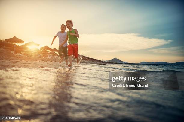 little boys running happily on the beach - drenched stock pictures, royalty-free photos & images