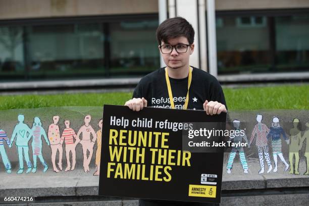 An activist holds up a giant paper chain and a placard during a demonstration in front of the Home Office on March 30, 2017 in London, England....