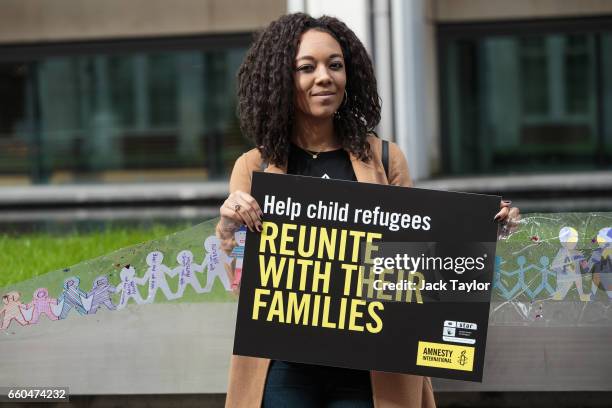 Katherine Odukoya, with the campaigns and community organising teams of Amnesty International UK, holds up a giant paper chain and a placard during a...