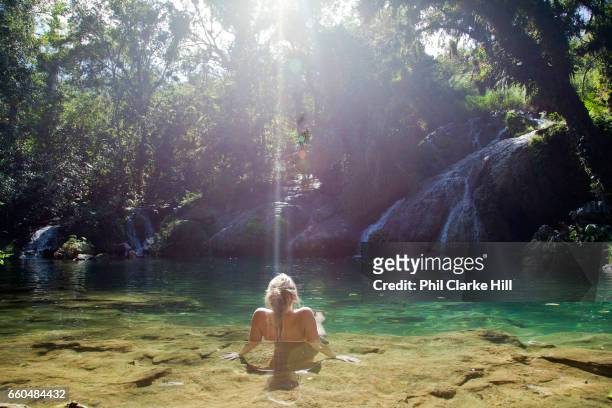 Young woman reclining relaxing in fresh water, El Nicho, in the forest between Ciengfuegos and Trinidade, Cienfuegos province, Cuba. .