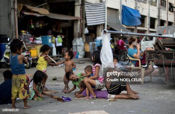 Homeless children play on a street at Divisoria market in Manila on March 30, 2017. / AFP PHOTO / NOEL CELIS