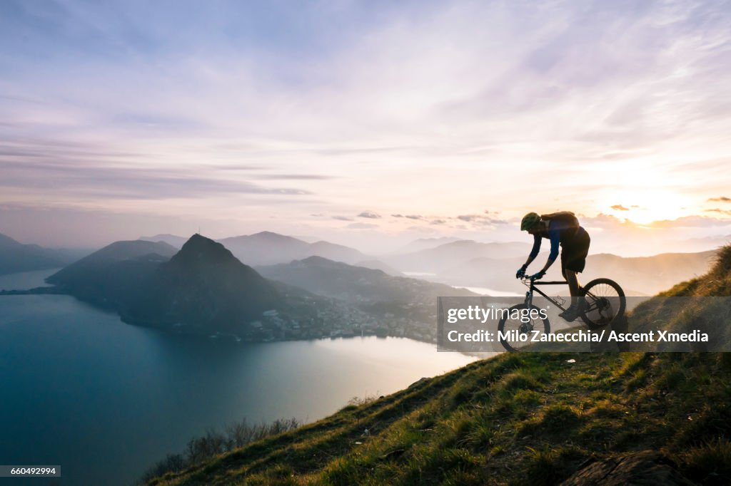 Mountain biker descends steep mountain slope above lake
