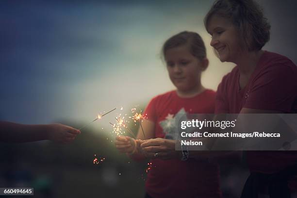 mother and daughters holding lit sparklers at fourth of july celebration - cultura americana stock pictures, royalty-free photos & images