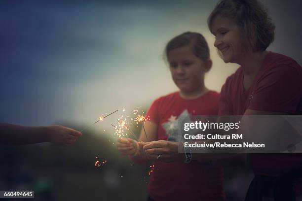 mother and daughters holding lit sparklers at fourth of july celebration - cultura americana 個照片及圖片檔