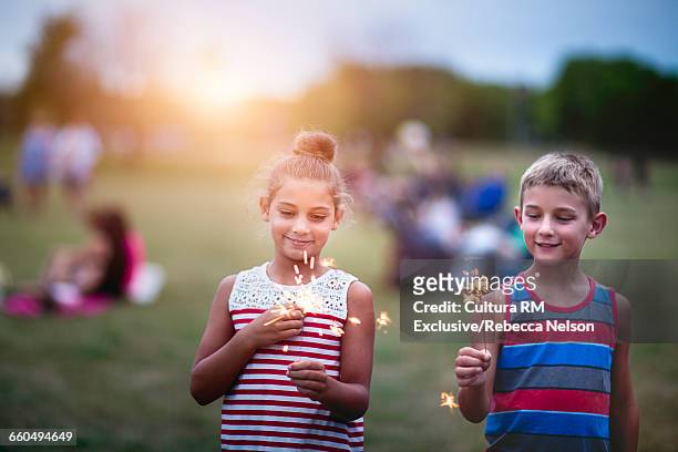 brother and sister holding lit sparklers at fourth of july celebration - cultura americana 個照片及圖片檔