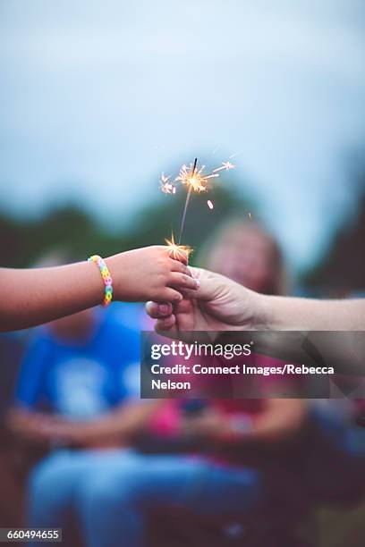 mans hand handing lit sparkler to child - cultura americana stock pictures, royalty-free photos & images