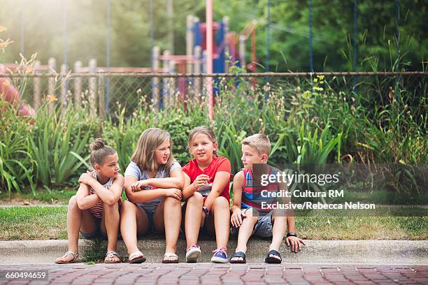 children having conversation on curb of cobblestone road waiting for fourth of july parade to begin - cultura americana stock-fotos und bilder