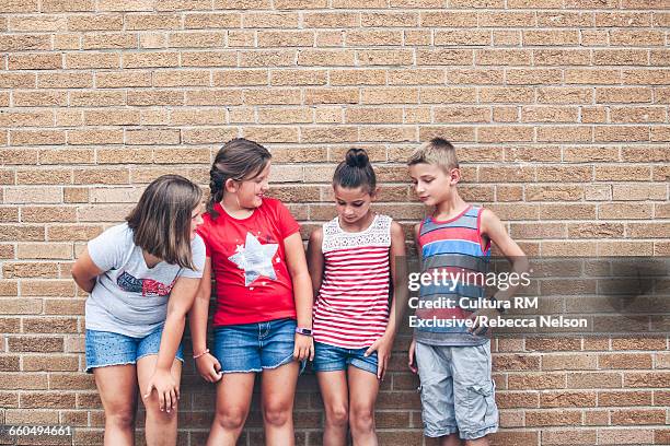 children leaning against brick wall having conversation - cultura americana stock pictures, royalty-free photos & images