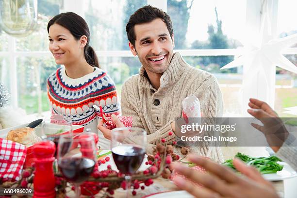 smiling man holding christmas cracker at dinner table - christmas crackers stock pictures, royalty-free photos & images