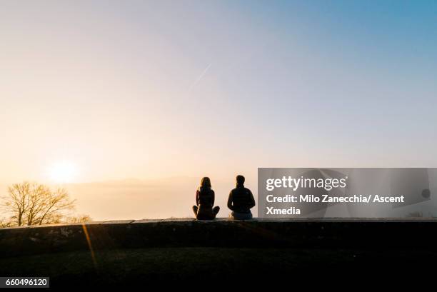 couple relax on stone wall above valley, sunrise - mid distance stock pictures, royalty-free photos & images