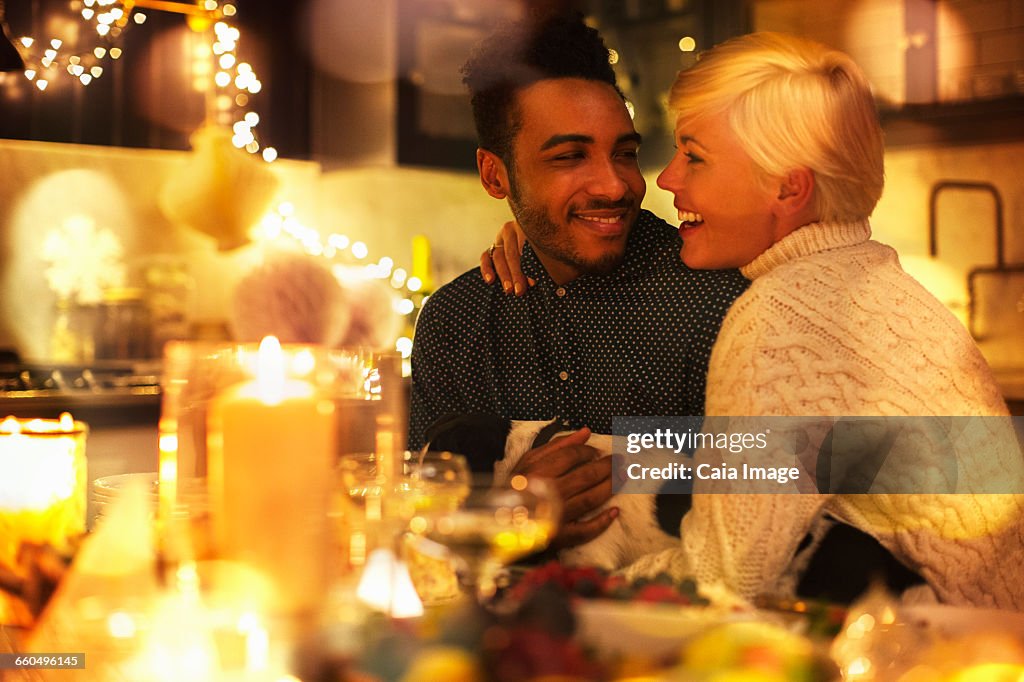 Affectionate couple with dog at candlelight Christmas table