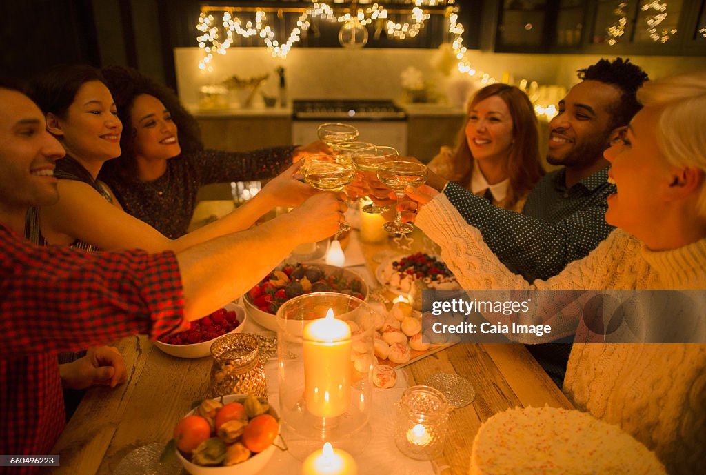 Friends toasting champagne glasses at candlelight table