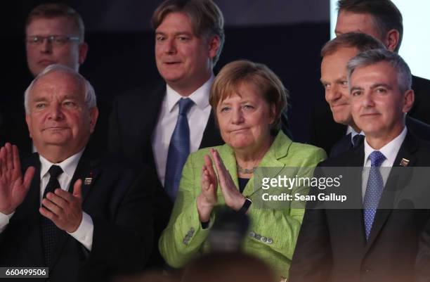 German Chancellor Angela Merkel , flanked by EPP President Joseph Daul and Malta Partit Nazzjonalista party leader Simon Busuttil , stands on stage...