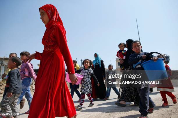 Iraqis fleeing their homes in Mosul's old city carry their belongings as they leave the fighting area on March 30 due to the ongoing battles between...