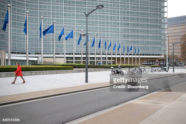 Pedestrian walks past the European Commission Berlaymont building as European Union flags fly in Brussels, Belgium, on Thursday, March 30, 2017....